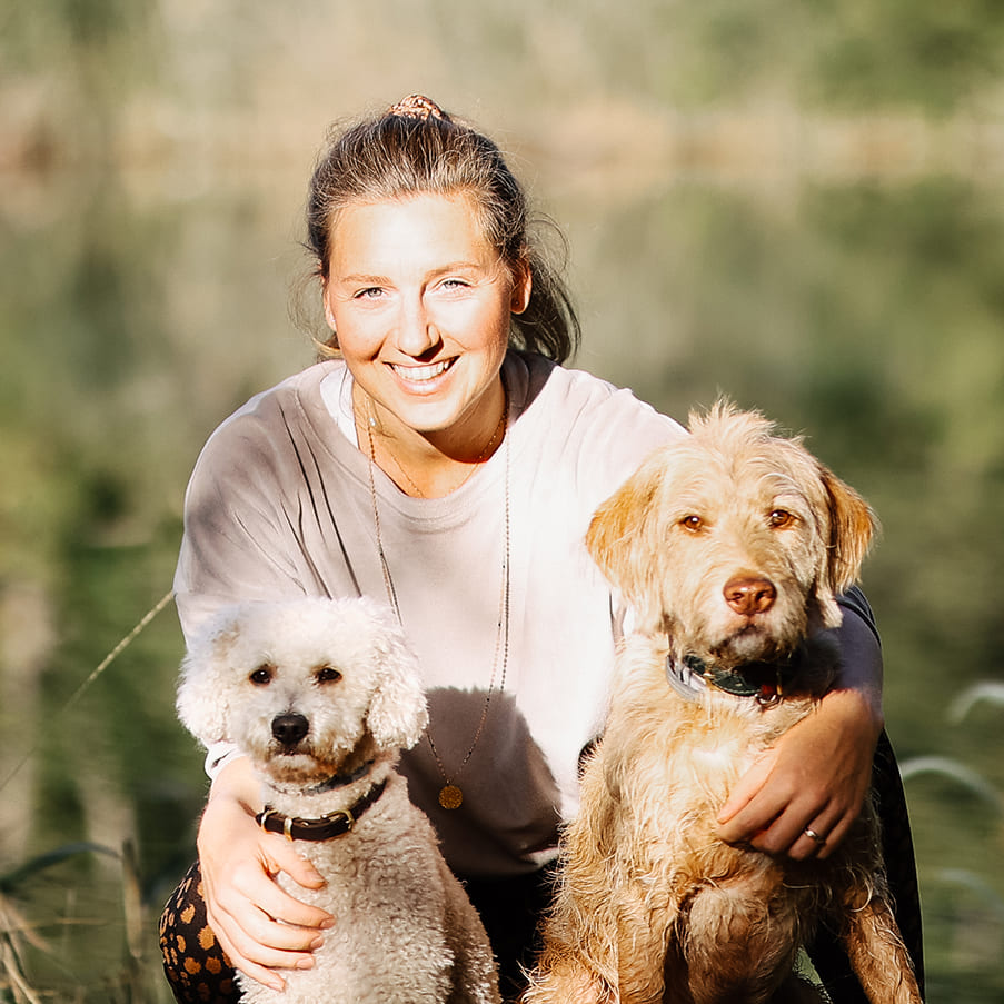 Hundetrainerin Sandra Vergien lacht in die Kamera, mit 2 Hunden in der Natur.
